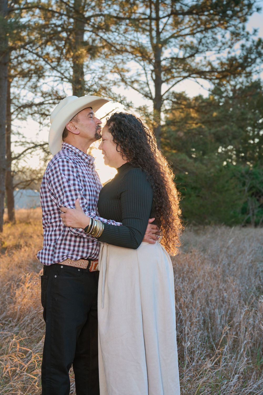 Couple sharing intimate moment outdoors in golden field at sunset.