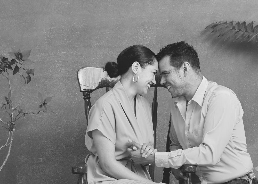 A vintage black and white photograph shows a tender romantic moment between two people leaning in close together.