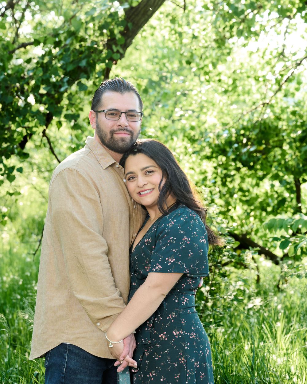 Couple embraces tenderly in spring garden with lush green foliage creating a romantic natural backdrop.