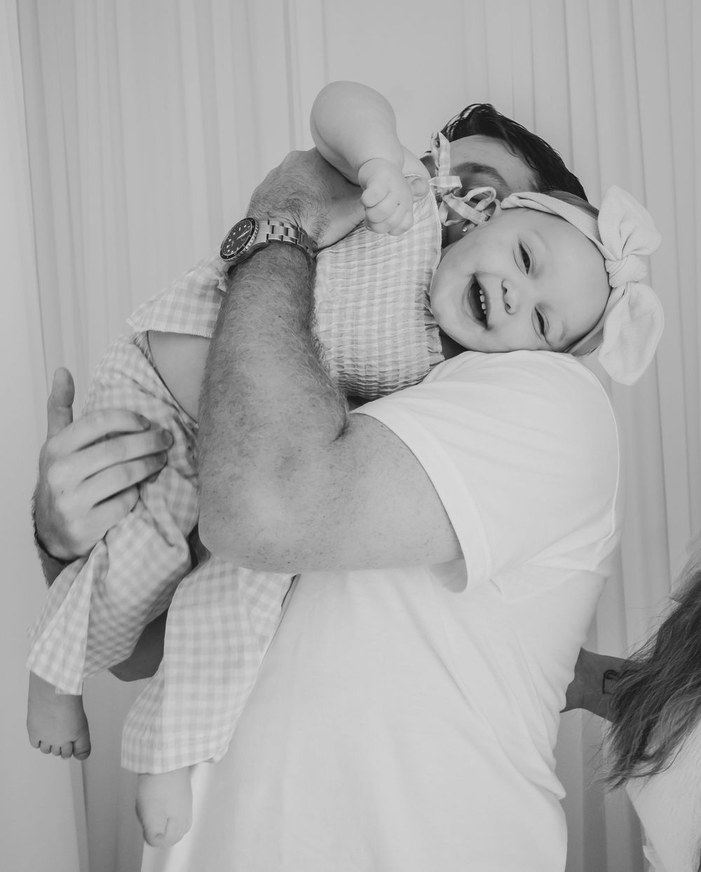 Dad holding daughter while she's laughing. Fun in studio, lifestyle family session.