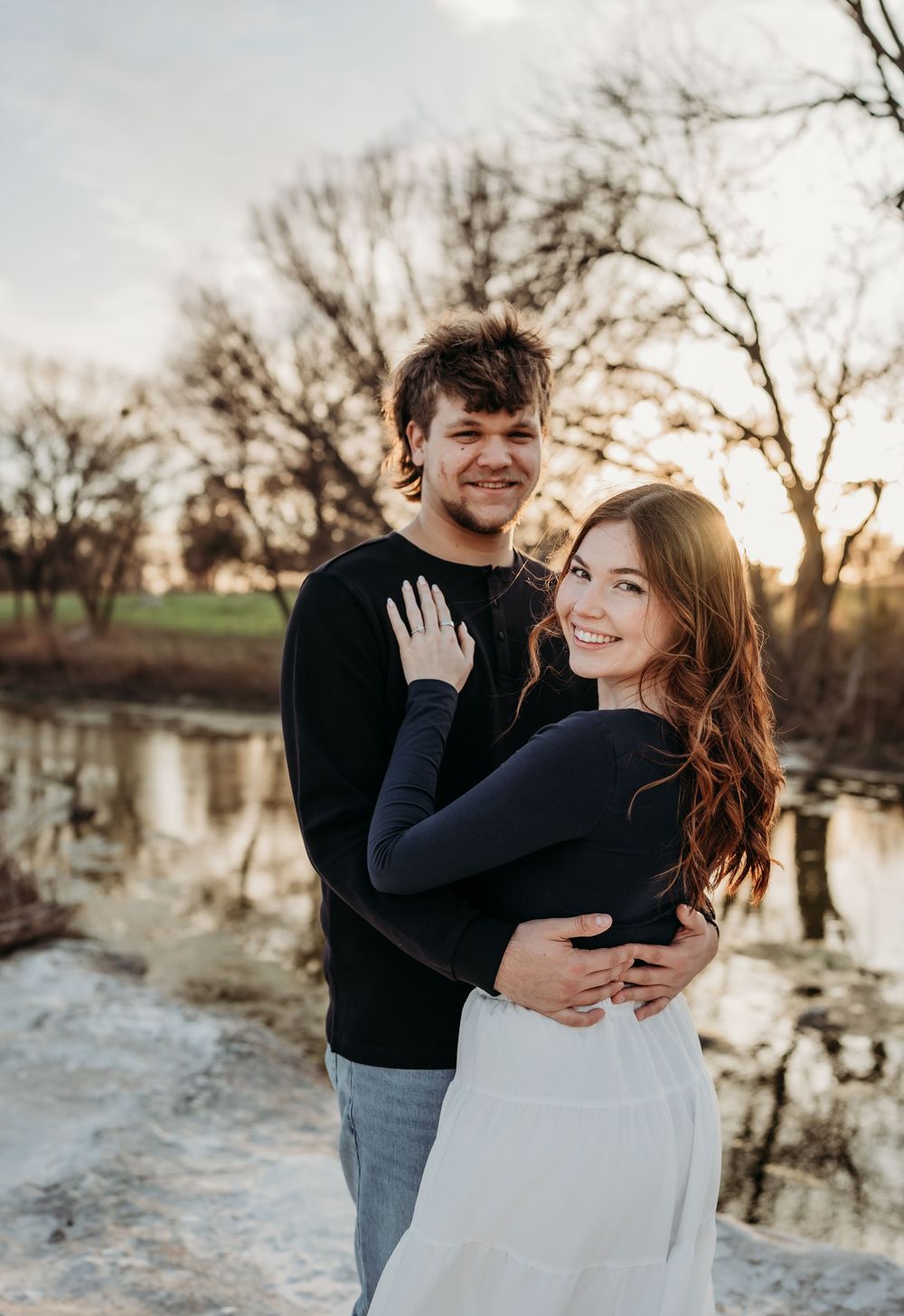 A couple shares romantic moments by a reflective pond at sunset, captured in a series of candid engagement photos.