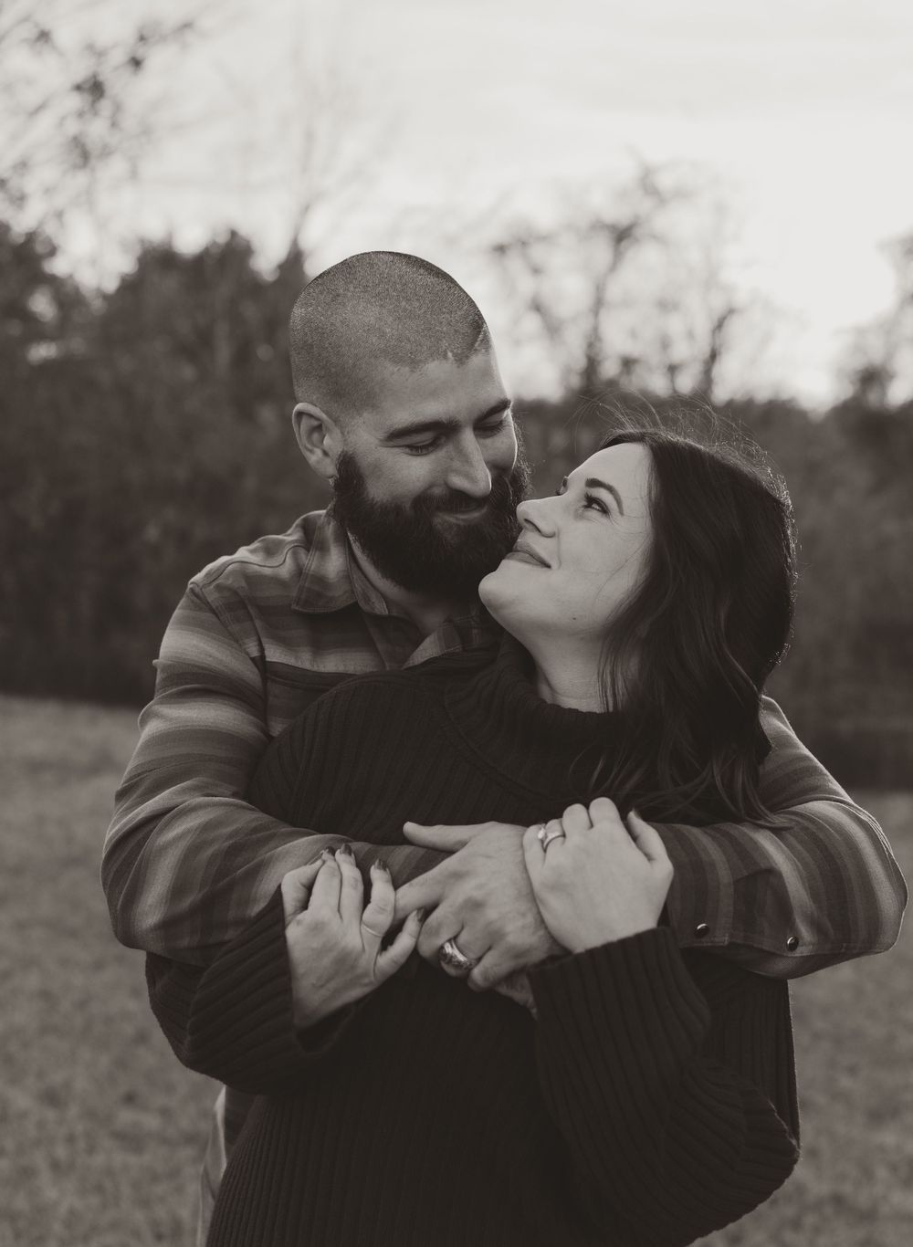 A romantic couple embraces in an intimate black and white photo series showing tender moments outdoors.
