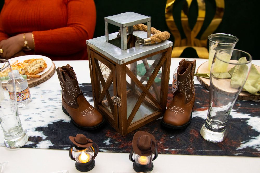 Table setting with decorative lantern, boots, and drinks for rustic themed celebration.