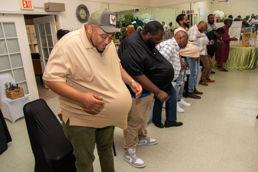 People stand in line waiting inside a community center hallway with beige walls and tiled floors.