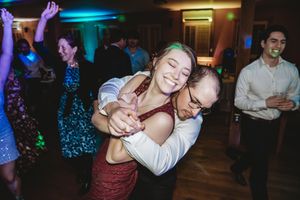 Couple joyfully dancing and embracing at a lively wedding reception with guests celebrating in background.