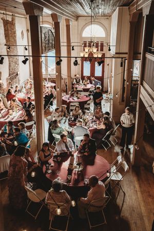 Aerial view of a rustic wedding reception with guests seated at round tables in an elegant historic venue.