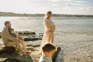 Family enjoying peaceful moment together by rocky oceanside.