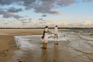 A family walking along Ramsgate Beach at Botany Bay during sunset, under a sky that resembles a painting with its soft,
