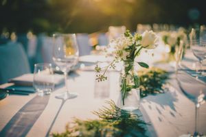 Elegant wedding table setting with delicate white floral centerpieces and wine glasses casting soft shadows.