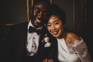 A joyful couple shares a loving moment at their wedding, with the bride in white lace and groom in classic tuxedo.