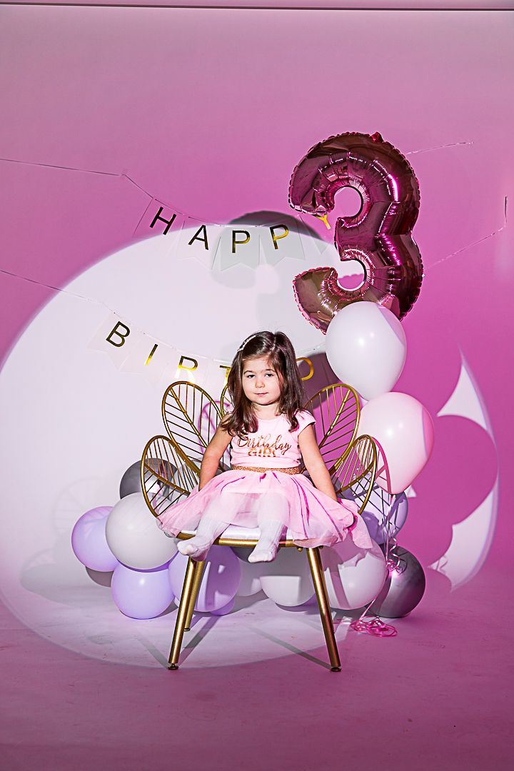 Pink and purple balloon display with fairy wings for magical birthday photoshoot.