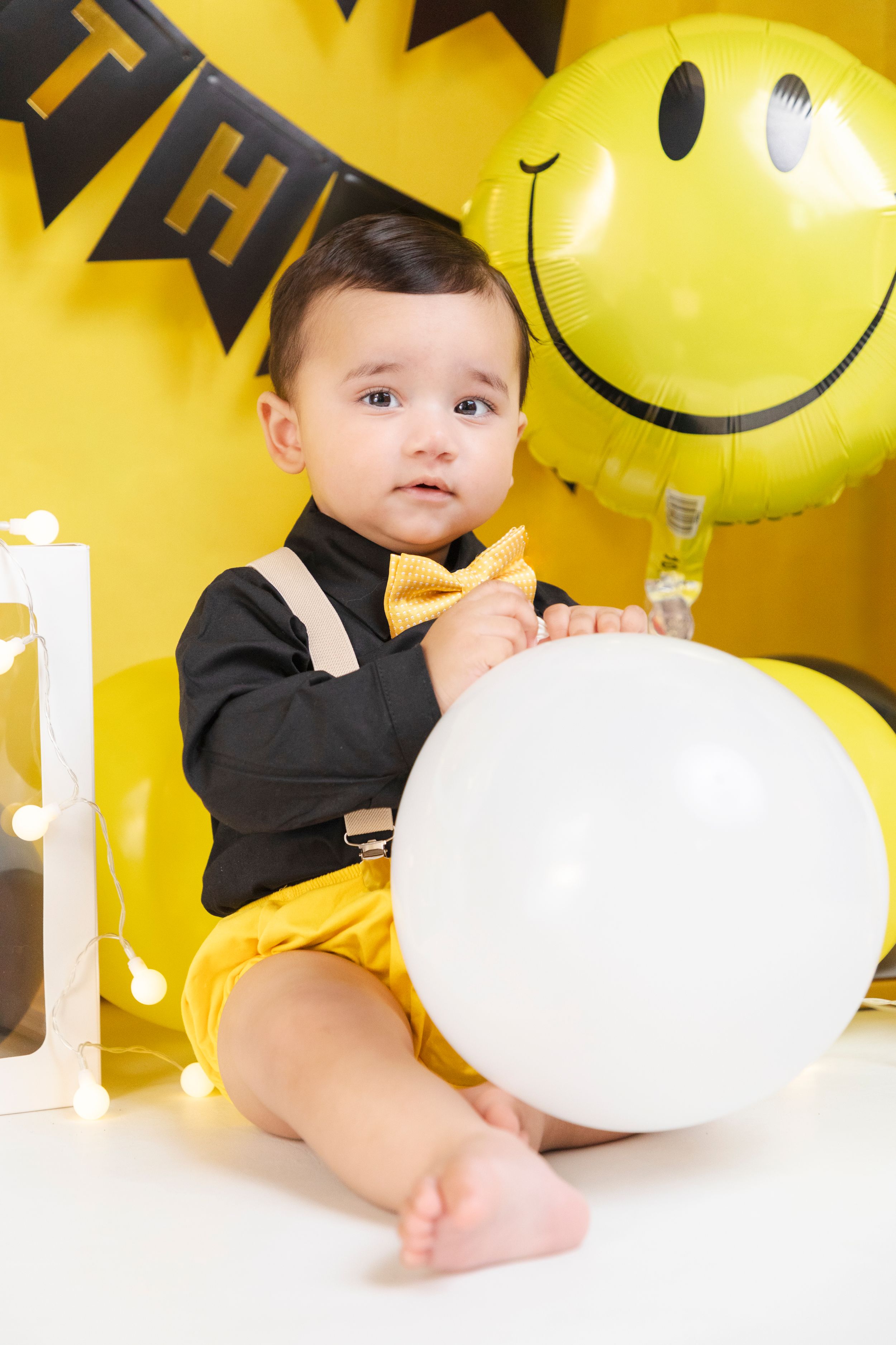 Yellow themed birthday setup with white balloon and smiley face decoration.