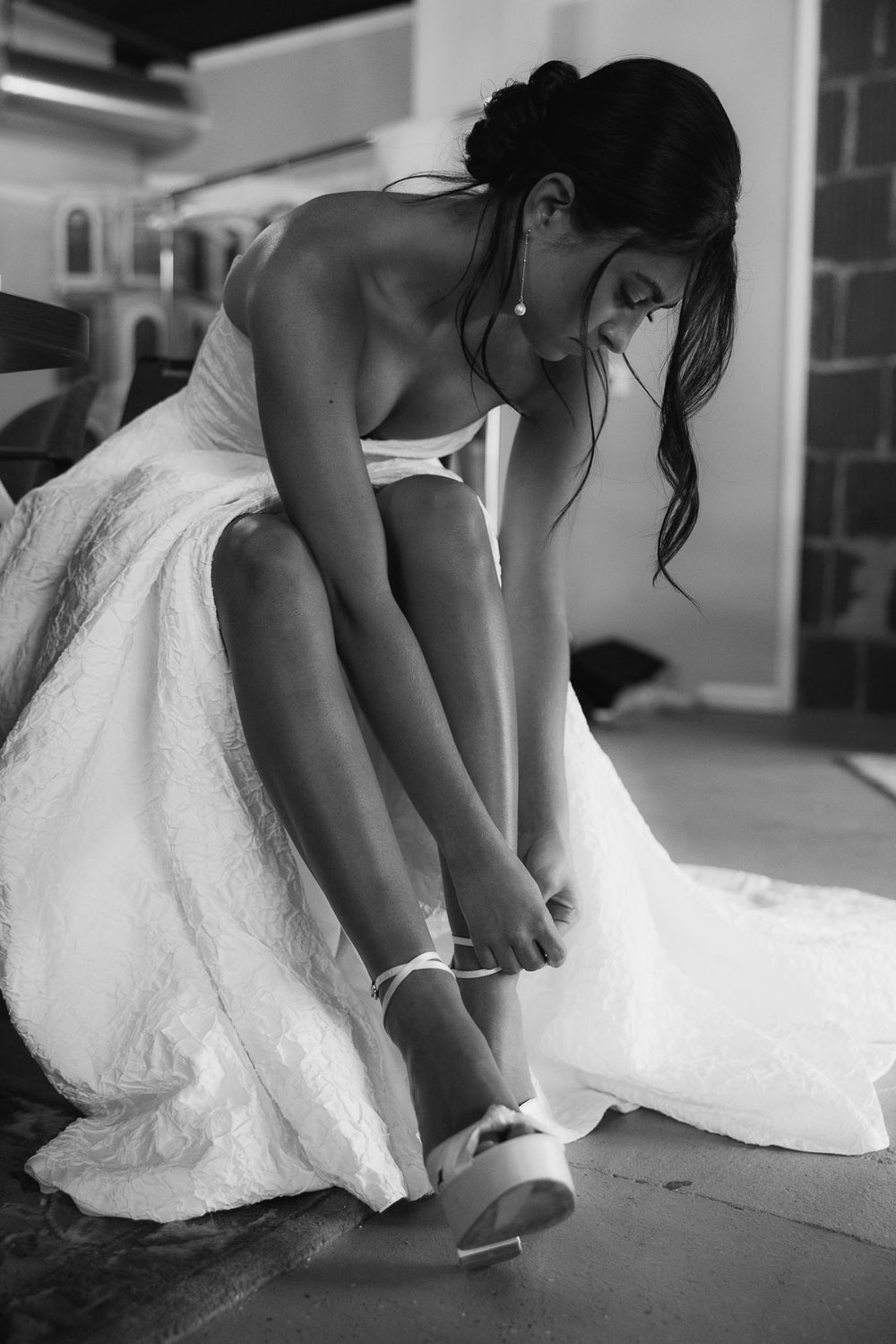 Bride getting ready by fastening her wedding heels in a quiet moment before the ceremony, captured by Cleveland wedding photographer.