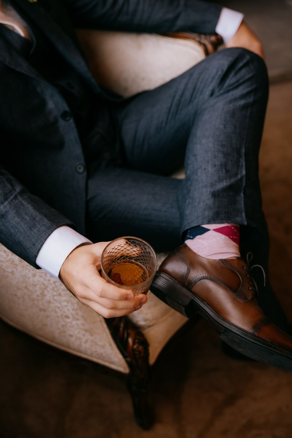 Candid photo of the groom relaxing in a chair with a whiskey captured by Cleveland wedding photographer.