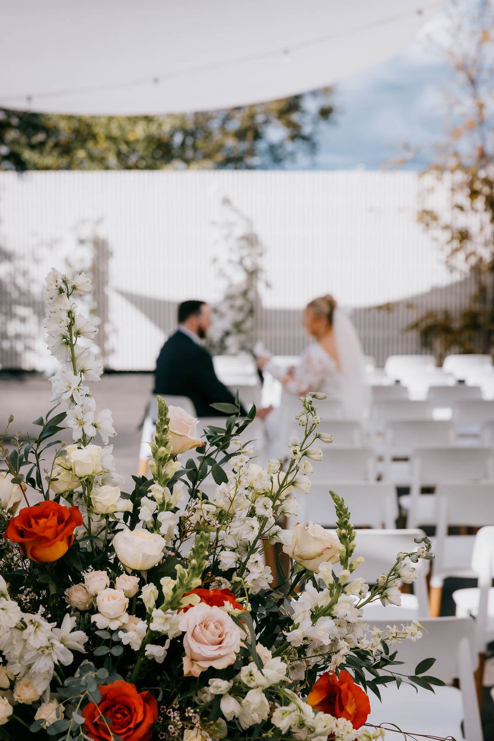 Wedding ceremony florals in focus as couple exchanges private vows, captured by Cleveland wedding photographer.