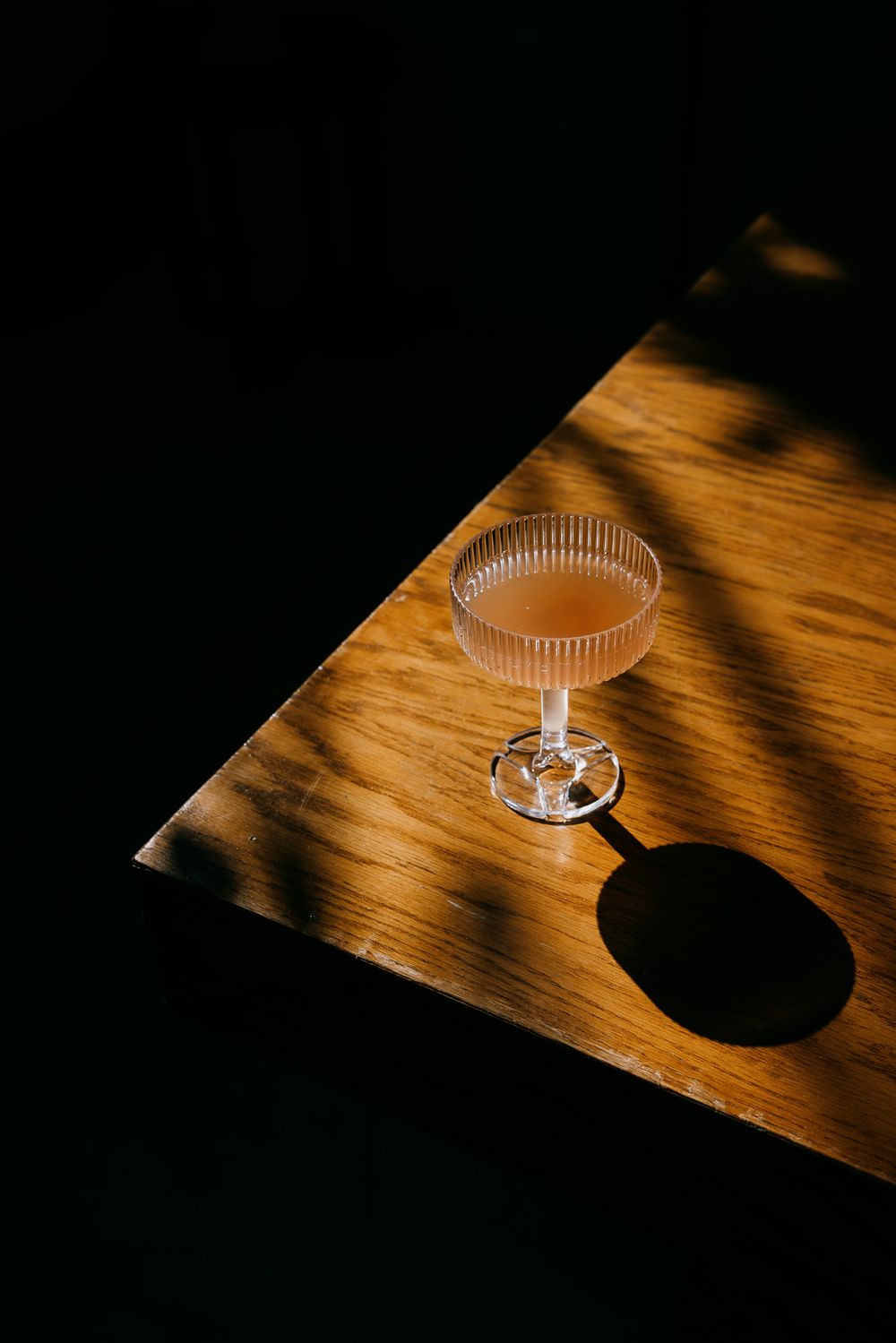 Moody wedding detail of a cocktail in crystal glass on wood table with an editorial edit, captured by Cleveland wedding photographer.