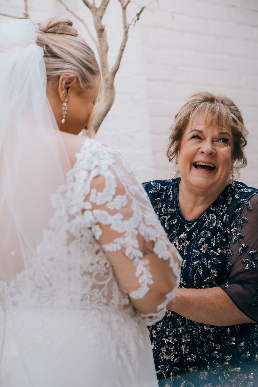 Mother of the bride sharing a joyful moment with her daughter while getting ready, captured by Cleveland wedding photographer.