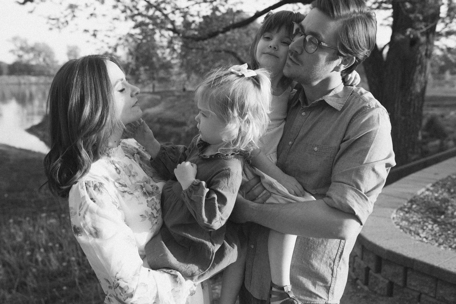 Black and white family photo by B.Logsdon showing parents with two small children in a natural setting.