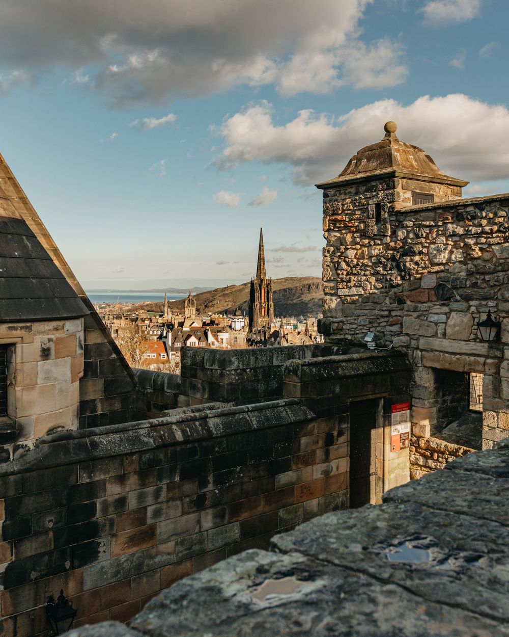 A panoramic view of Edinburgh city from the historic stone walls of Edinburgh Castle at sunset.