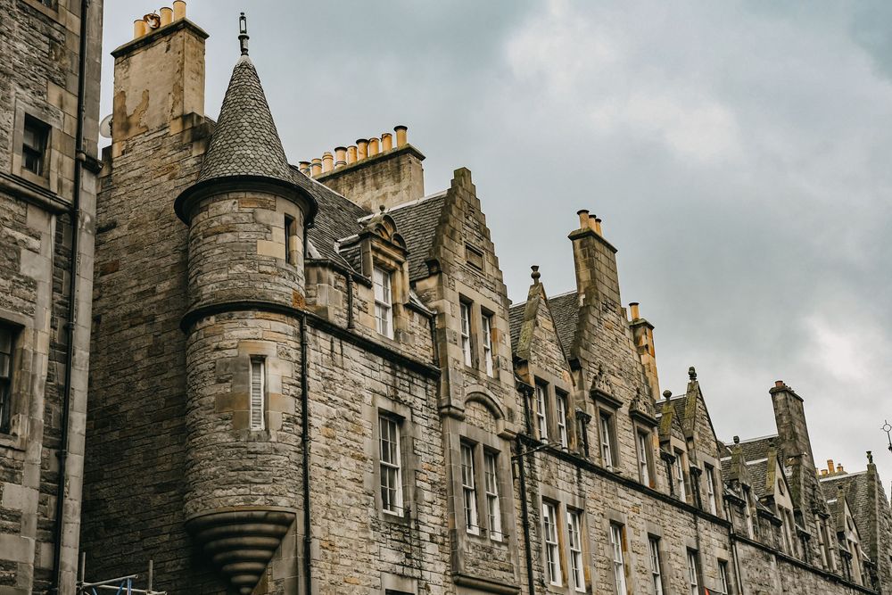 Historic Scottish stone castle with turrets and Gothic architecture under a cloudy sky.