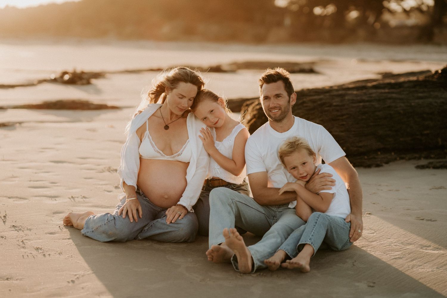 Intimate family moment as parents sit with their children on white backdrop.
