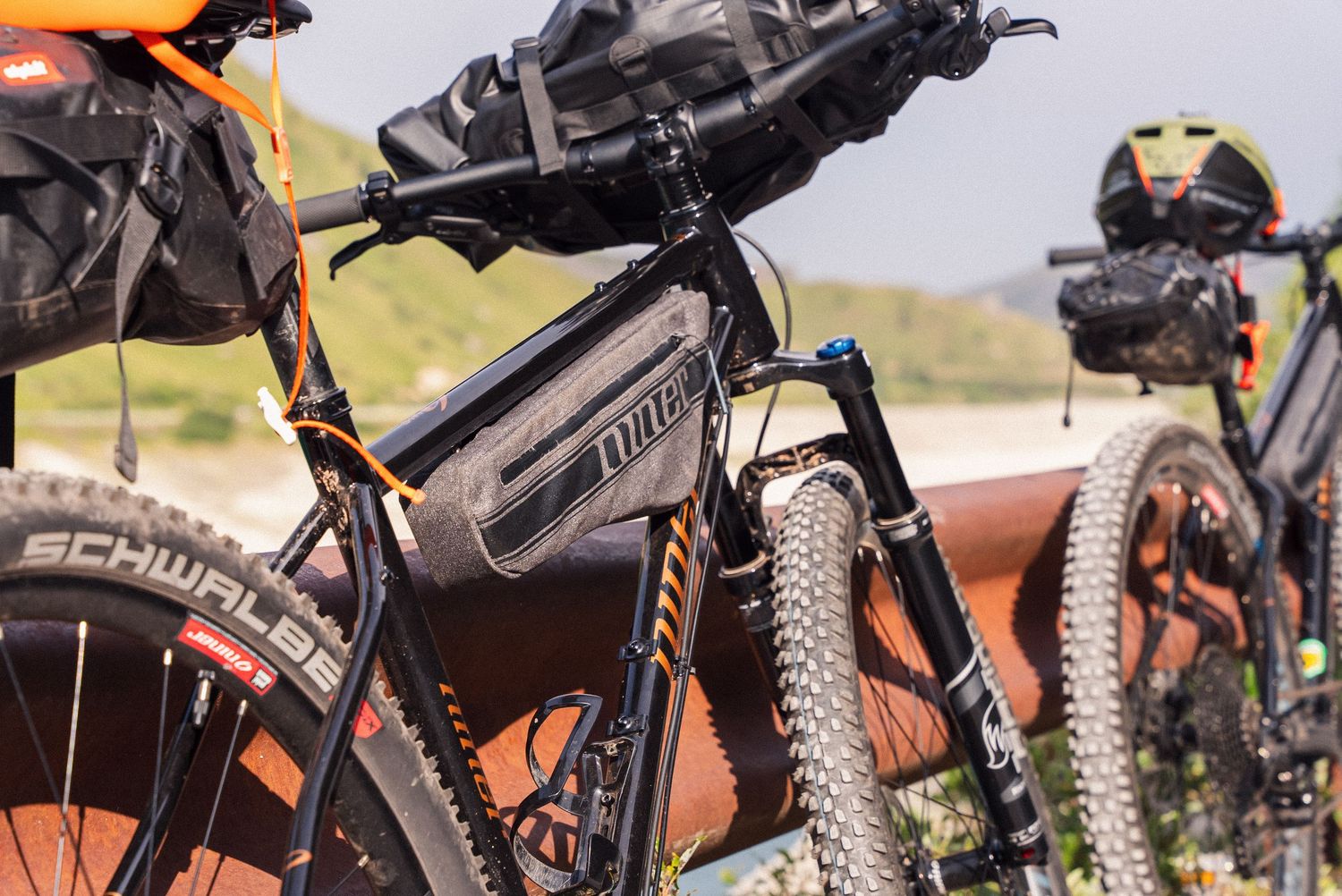 Close-up view of mountain bike components and tires against an orange sunset sky background.