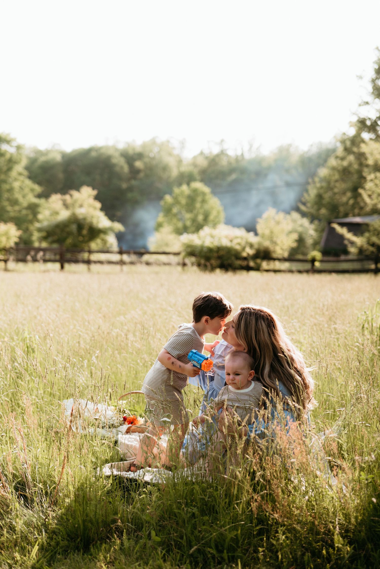 Joyful family of four playing together in a golden autumn meadow, children raising their hands.