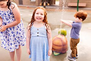 Children playing outdoors near a decorative pumpkin on a sunny day.