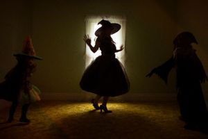 Silhouettes of people in witch costumes dancing in a dimly lit room.