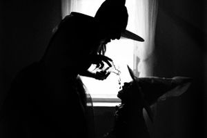 Dramatic silhouette of person in hat against window light.