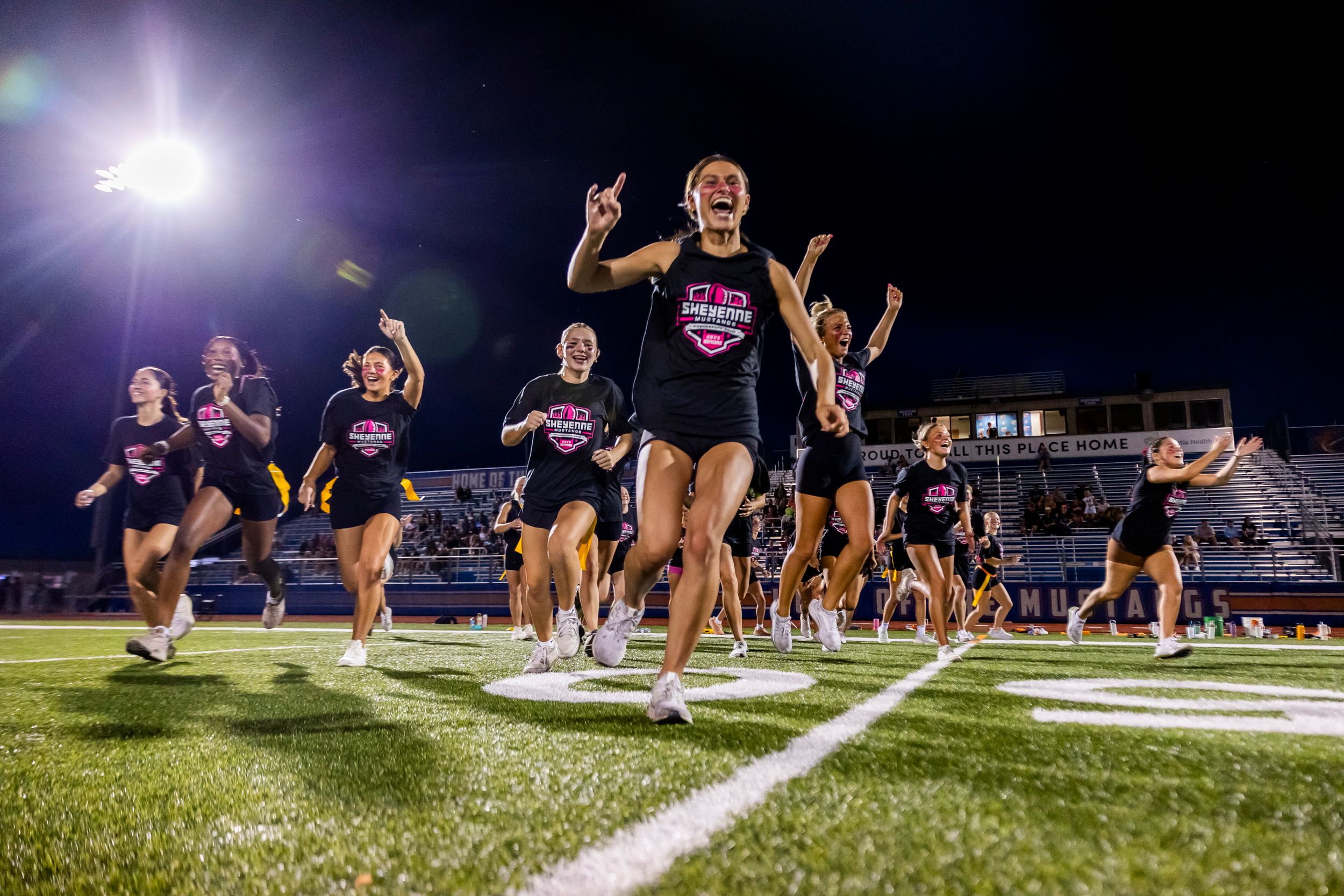 Dancers performing on football field under stadium lights at night.