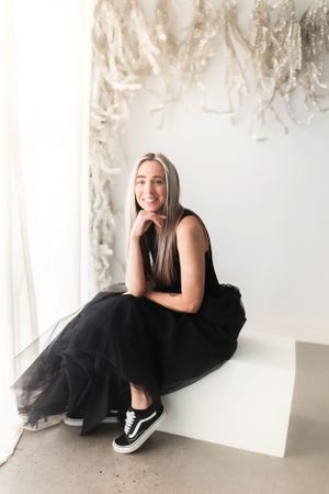 Portrait series against white wall with hanging decorative elements.