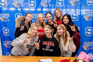 Group portrait in front of blue branded backdrop with collegiate sports logos.
