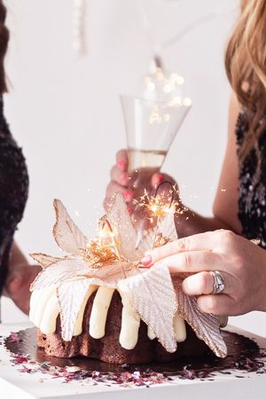 Close-up of hands holding a dessert with sparklers and decorative flower on top.