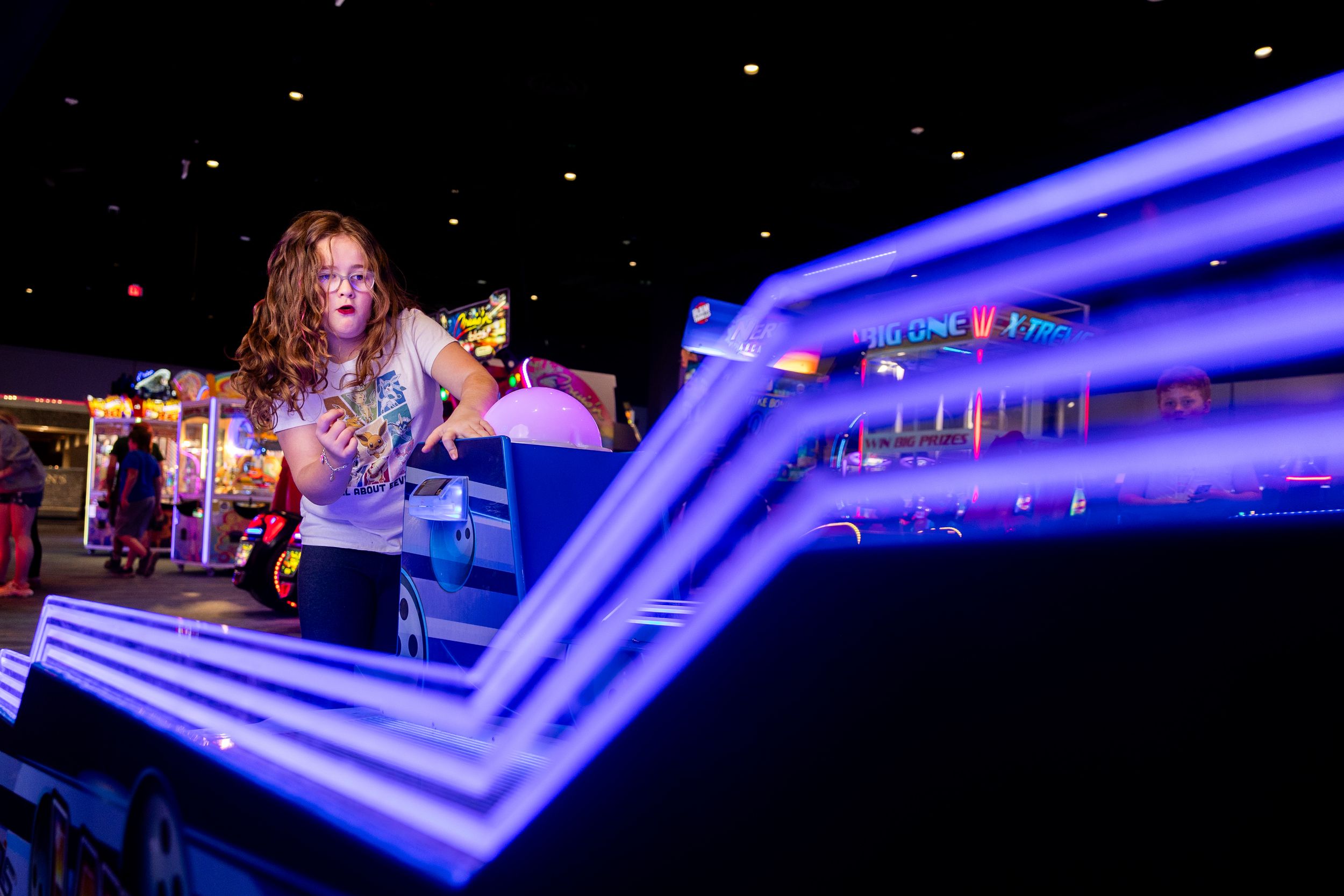 Performer plays guitar on stage with dramatic blue lighting effects and geometric patterns in the background.