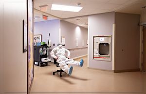 Empty hospital hallway with fluorescent lighting and medical equipment.