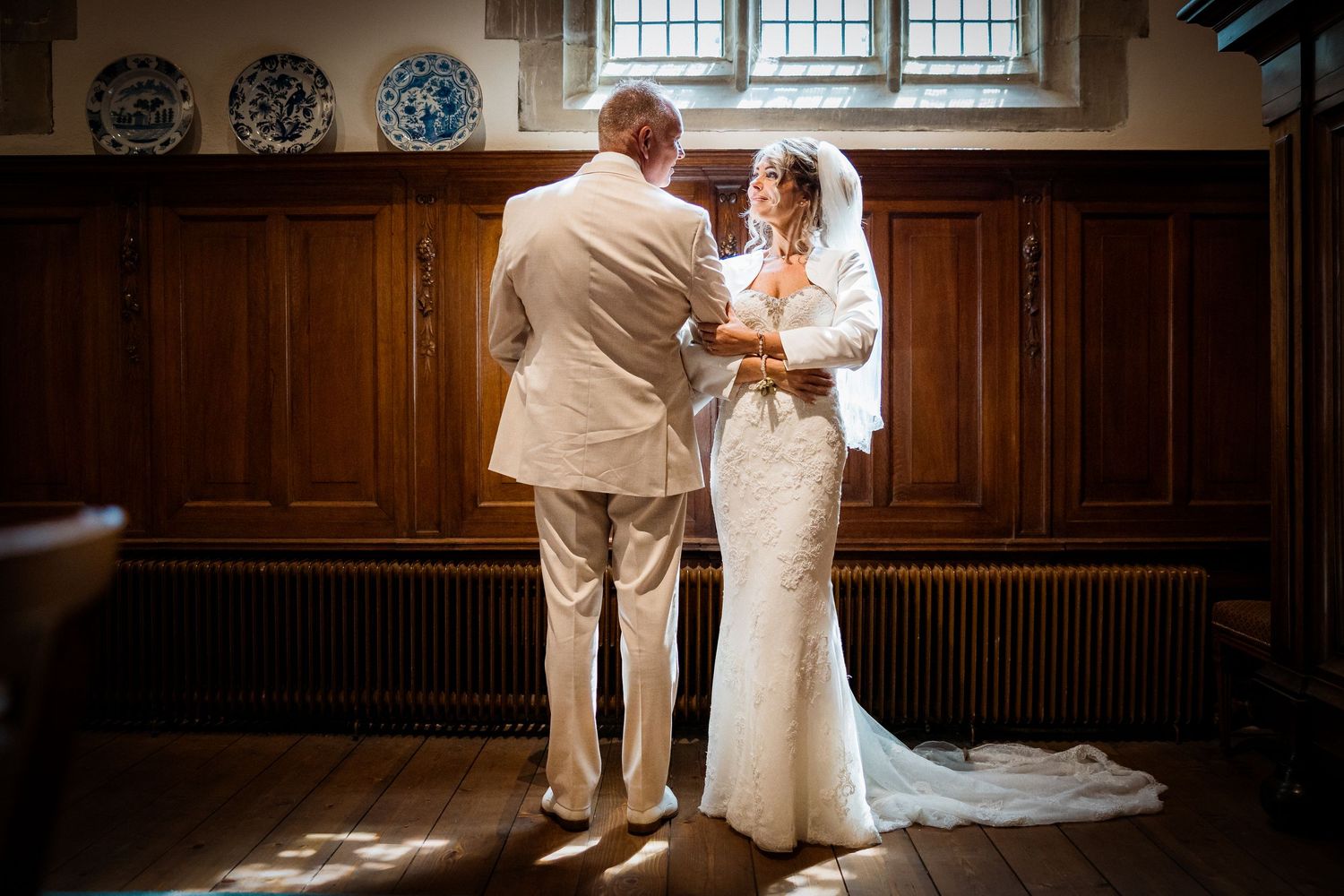 A couple shares a romantic moment during their wedding ceremony in a grand wood-paneled church interior.