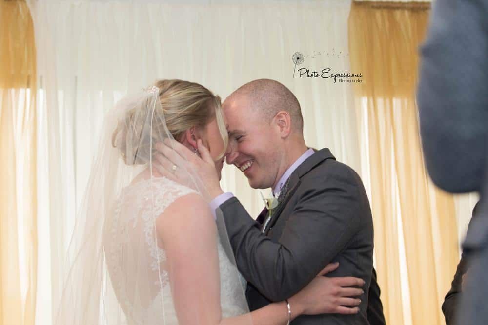 Wedding couple sharing intimate moment in front of sheer curtains.