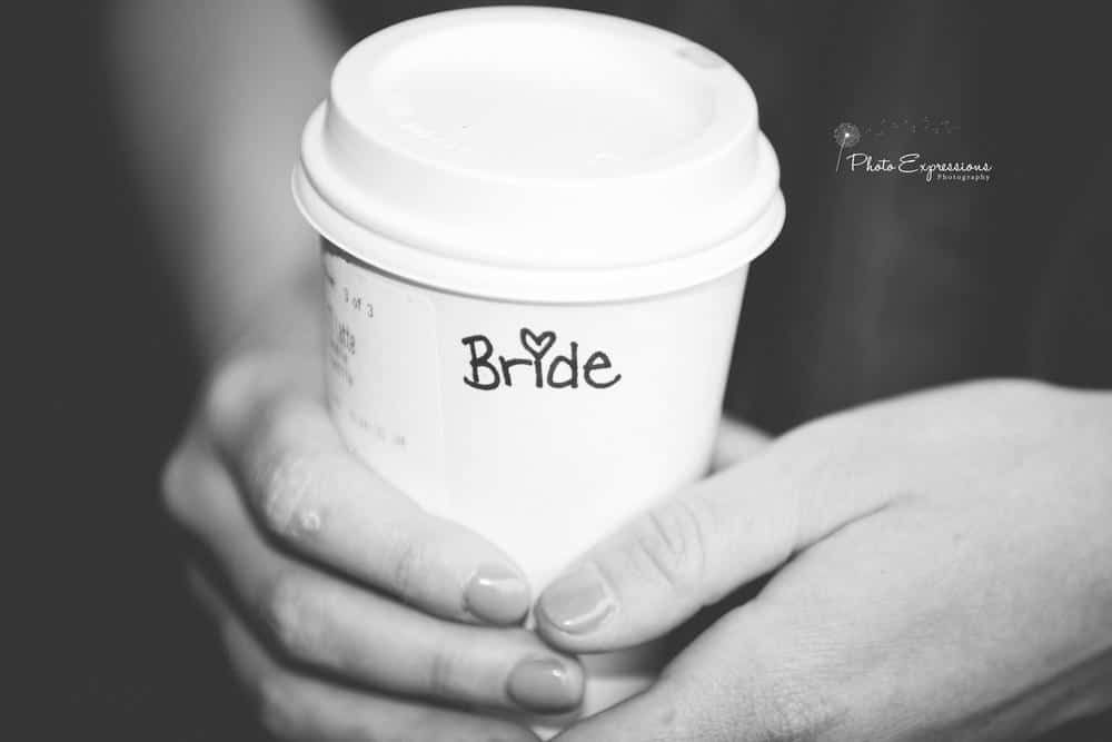 Black and white image of hands holding a coffee cup with 'Bride' written on it.