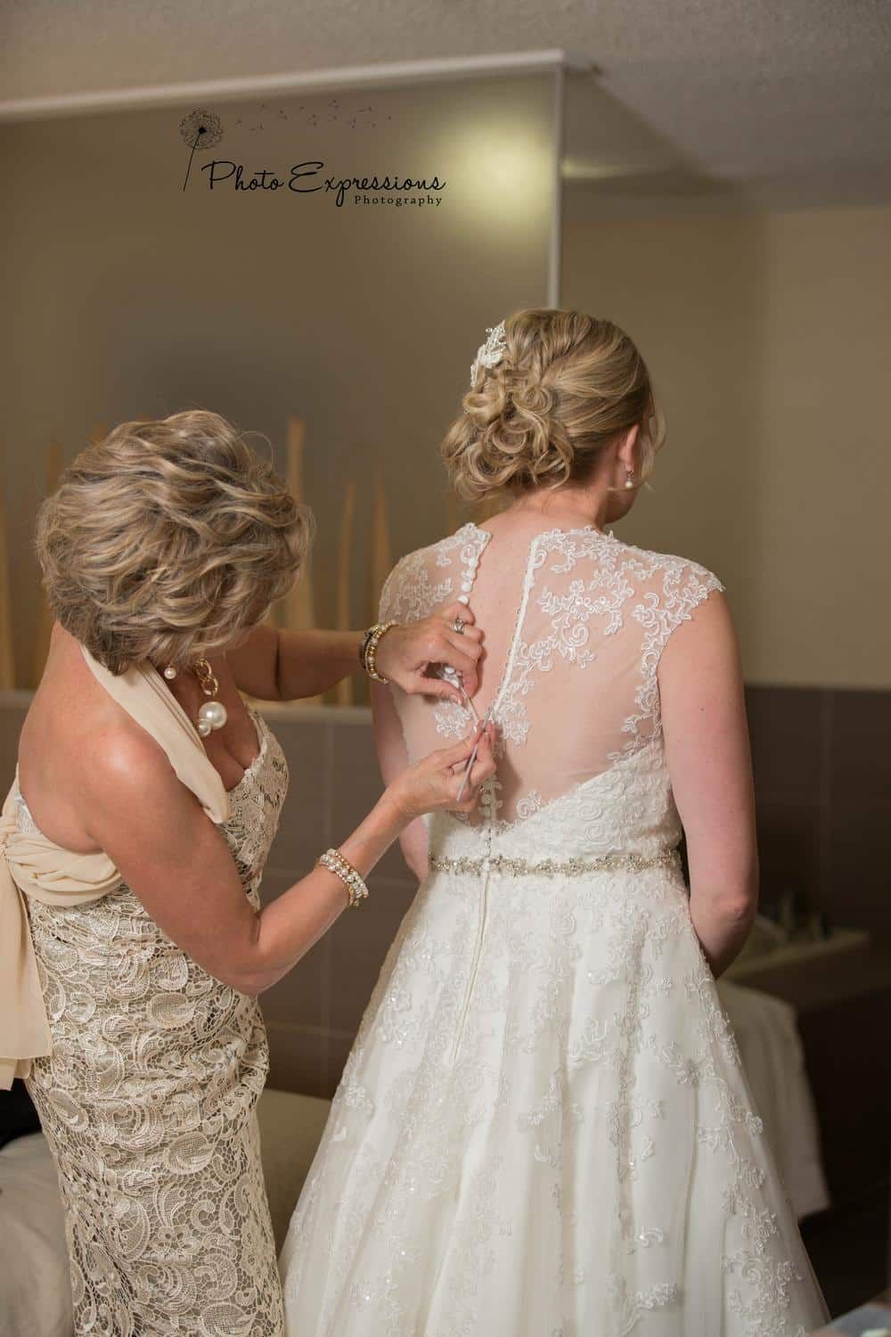 Close-up of intricate lace details on a wedding dress being fastened.