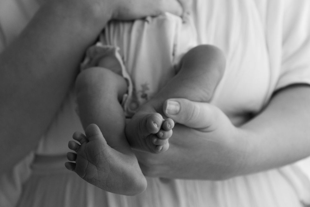 Close-up detail shots of gentle hands cradling little feet in soft light.
