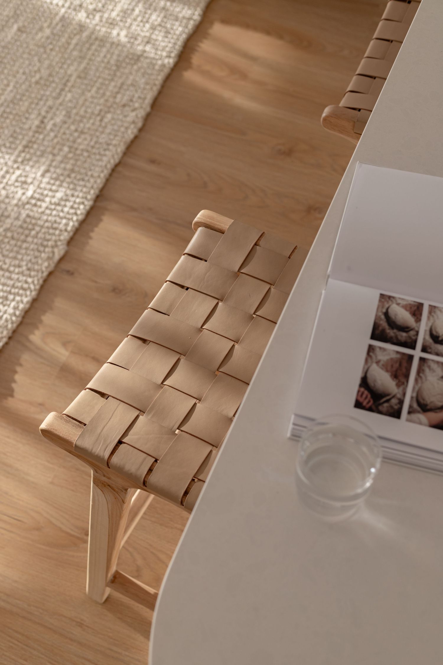 Modern woven leather dining chair cushion against light wooden floor in minimalist interior setting.