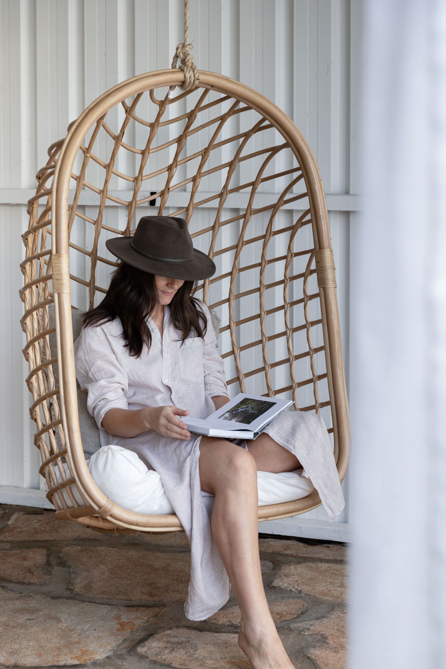 Rattan hanging chair with reading nook setup in white modern space.