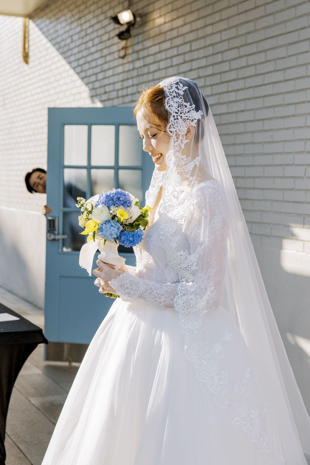 Wedding photos against a white brick wall featuring a traditional white gown and blue door details.