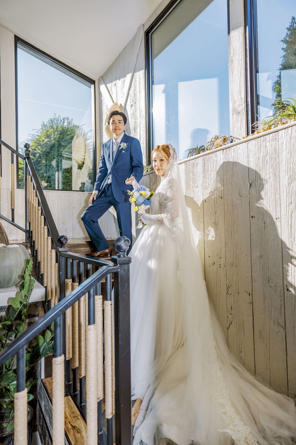 Wedding photography sequence on a white staircase with glass walls and natural lighting.