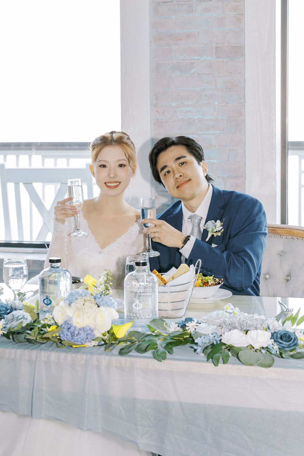 Festive wedding table decorated with blue and white flowers and greenery.
