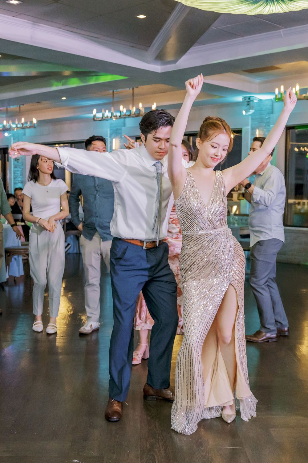 Couples dancing with enthusiasm at a wedding reception under modern ceiling lighting.