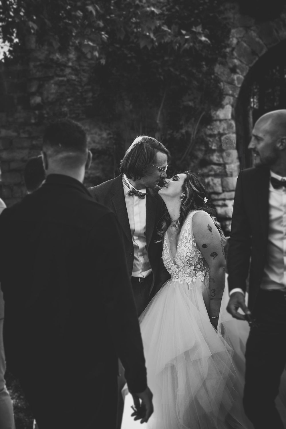 Black and white wedding ceremony photograph with guests and flowing white dress in motion.