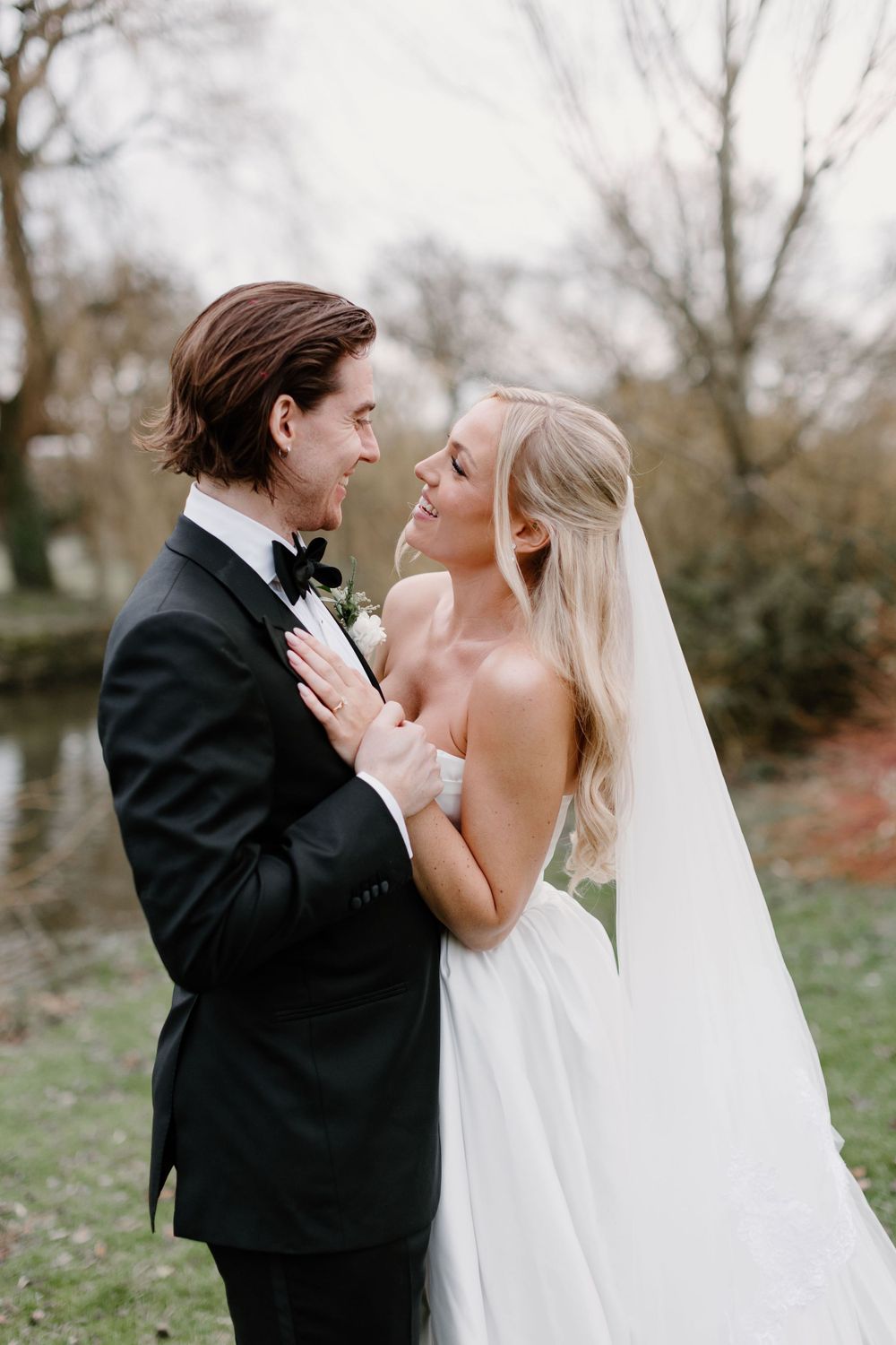 Romantic wedding couple embracing in an outdoor setting with autumn trees in the background.