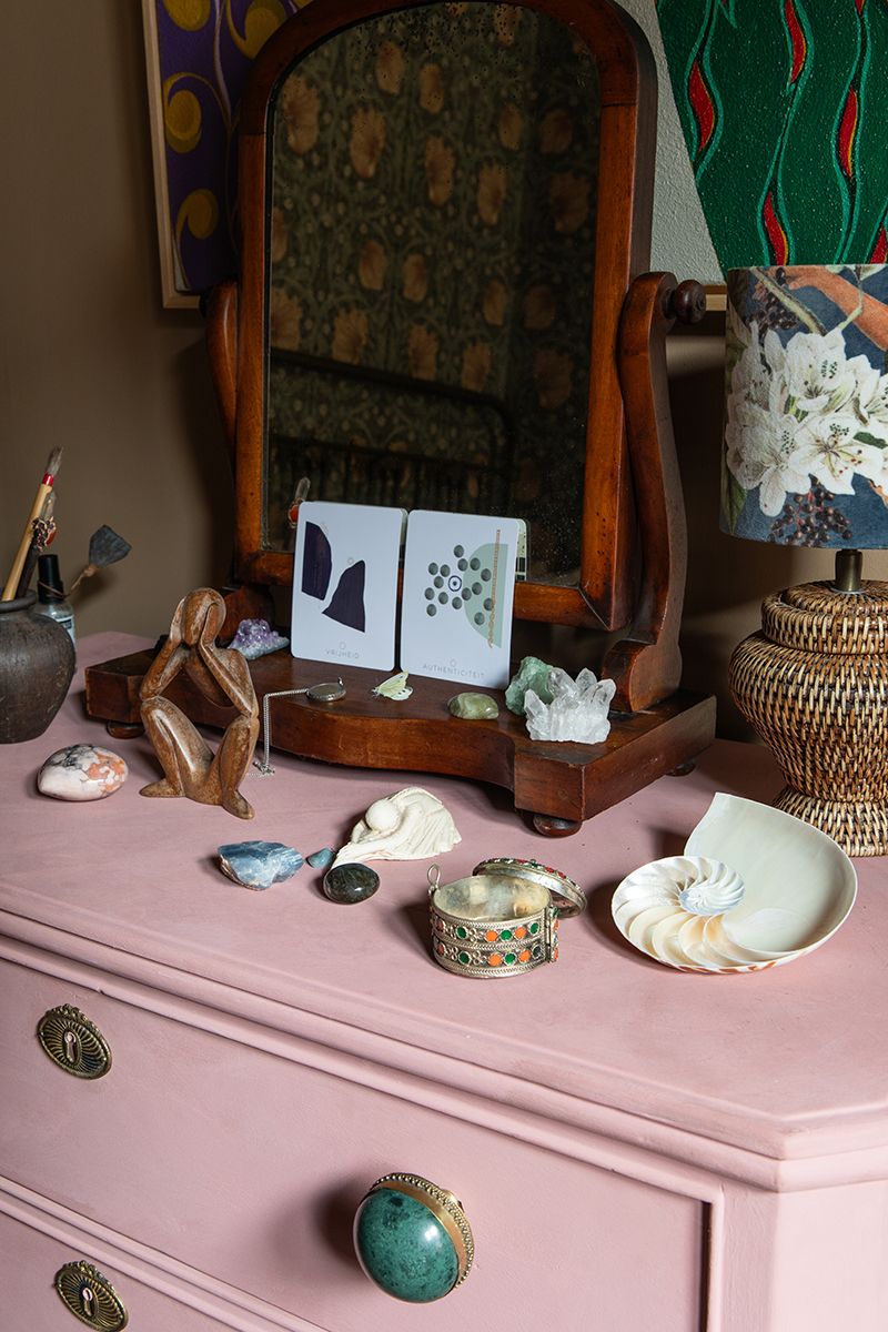 Interieurfoto van een roze kast met vintage woonaccessoires en persoonlijke spullen.